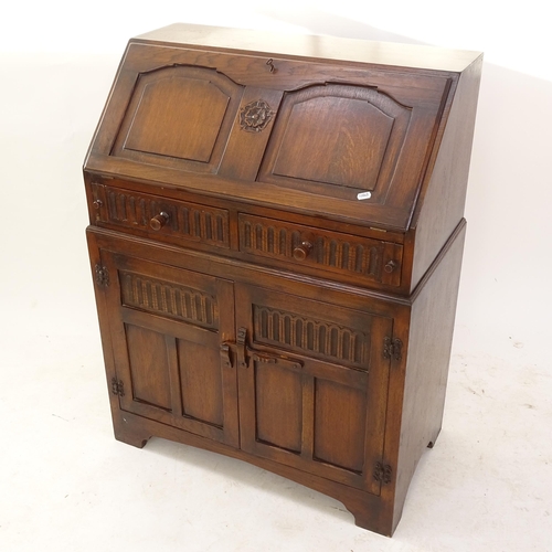 2074 - A linenfold carved and panelled oak bureau with cupboard doors, W77cm, H101cm, D41cm