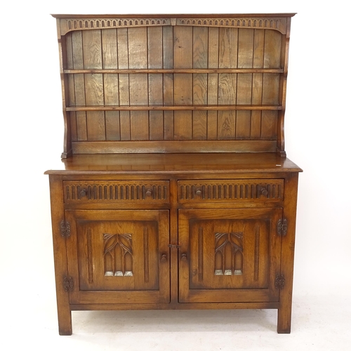 2076 - An oak dresser with boarded open plate rack, with 2 frieze drawers, and carved and panelled cupboard... 