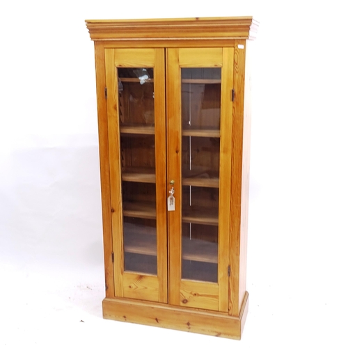 2134 - A polished pine bookcase, with 2 glazed doors and adjustable shelves, W76cm, H152cm, D32cm