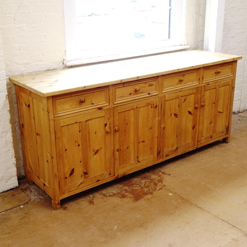 2143 - A large polished pine dresser base, having 4 frieze drawers with 4 panelled cupboard doors under, L2... 