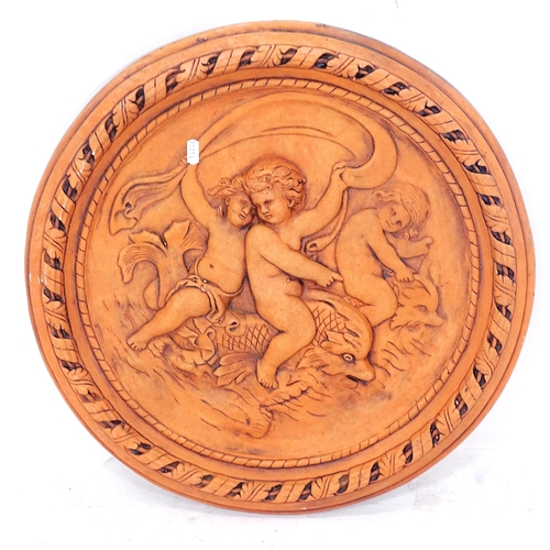 2317 - A terracotta garden plaque, depicting children riding sea monsters, diameter 55cm