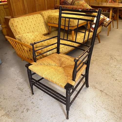 2677 - Liberty - an Antique ebonised Sussex style elbow chair with rush seat