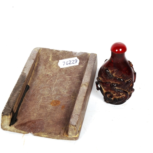 819 - A Chinese slate ink stone, and a small red amber snuff bottle (2)