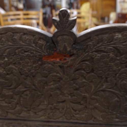 2250 - An ornate ebonised Victorian armchair, with allover relief carved decoration and cane panel seat