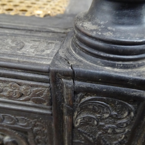 2250 - An ornate ebonised Victorian armchair, with allover relief carved decoration and cane panel seat