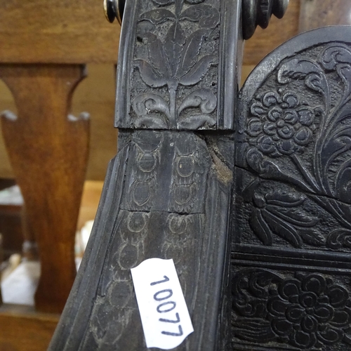 2250 - An ornate ebonised Victorian armchair, with allover relief carved decoration and cane panel seat