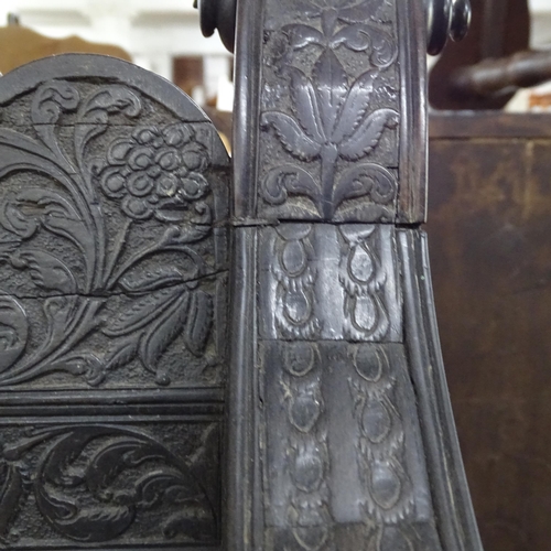 2250 - An ornate ebonised Victorian armchair, with allover relief carved decoration and cane panel seat