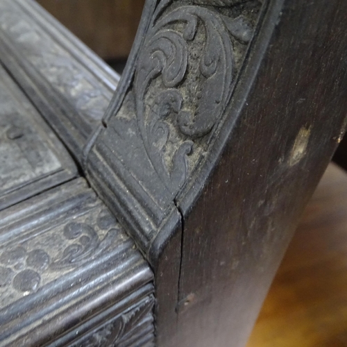 2250 - An ornate ebonised Victorian armchair, with allover relief carved decoration and cane panel seat