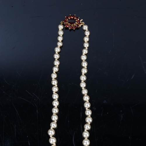 202 - A Vintage graduated single-row pearl necklace, with garnet set 9ct gold clasp, hallmarks London 1985... 