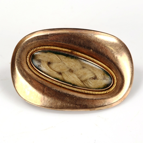 206 - A small Georgian unmarked gold mourning brooch, central oval woven hair panel under convex glass wit... 