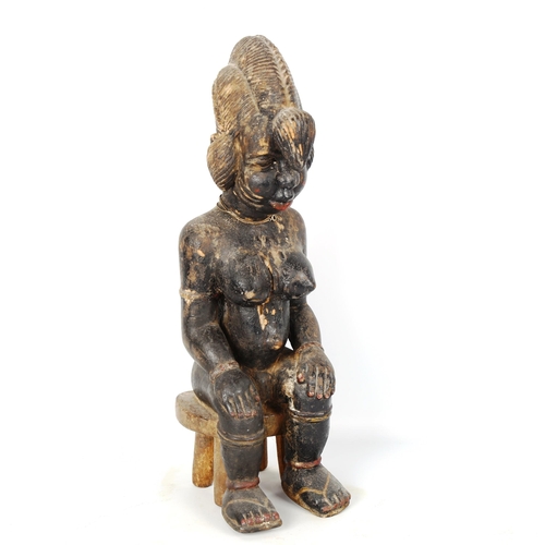 1023 - African carved and painted wood female seated figure, height 39cm