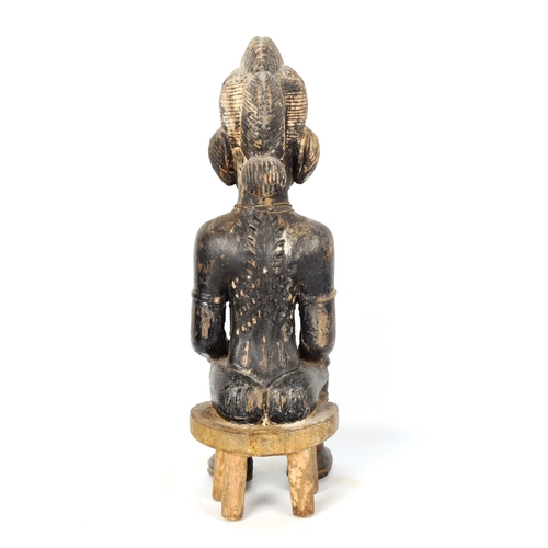 1023 - African carved and painted wood female seated figure, height 39cm