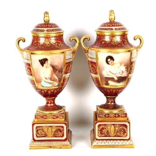 1121 - A fine pair of early 20th century Vienna porcelain urns and covers, with hand painted panels depicti... 