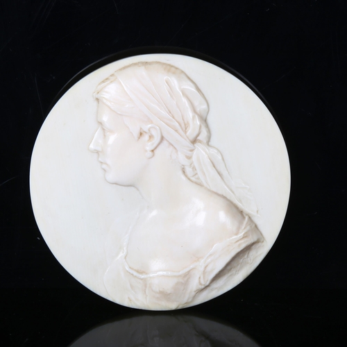 1132 - A circular relief carved ivory plaque, depicting portrait of a young woman, signed on reverse R Hall... 