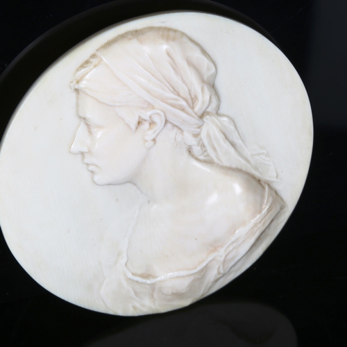 1132 - A circular relief carved ivory plaque, depicting portrait of a young woman, signed on reverse R Hall... 