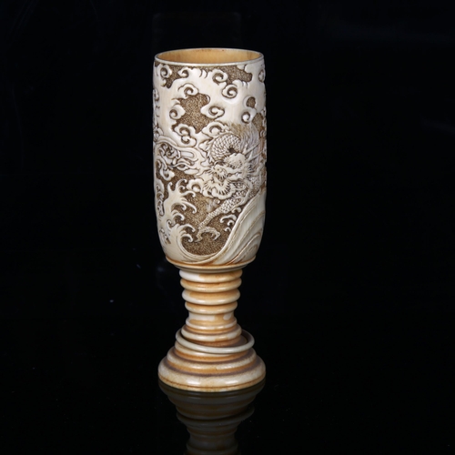 1134 - A Japanese ivory goblet circa 1900, the bowl relief carved with sea dragons, and ring turned base wi... 