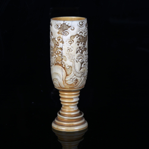 1134 - A Japanese ivory goblet circa 1900, the bowl relief carved with sea dragons, and ring turned base wi... 