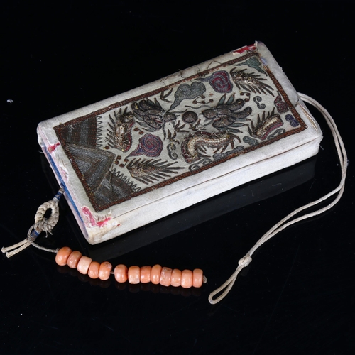 1135 - A Chinese embroidered silk case, containing a blue silk covered notebook and a short string of coral... 