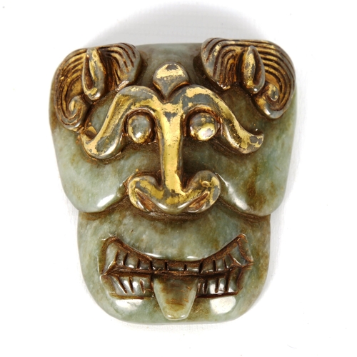 1141 - A Chinese carved jadeite buckle in the form of a mask, with gilded highlights, height 7.5cm