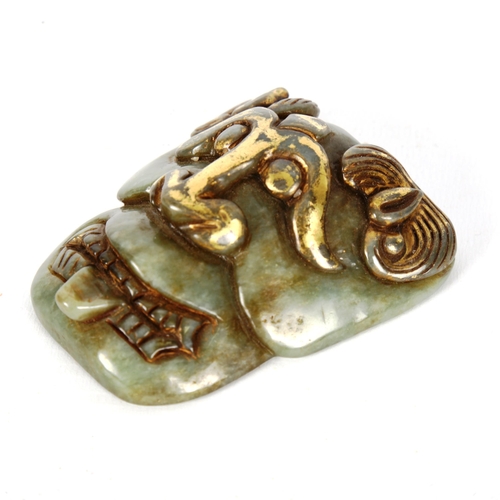 1141 - A Chinese carved jadeite buckle in the form of a mask, with gilded highlights, height 7.5cm