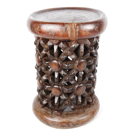 1355 - A small African stained wood drum-shaped stool with lattice pierced carved side, carved from a singl... 