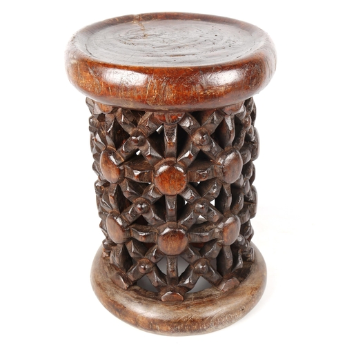 1355 - A small African stained wood drum-shaped stool with lattice pierced carved side, carved from a singl... 