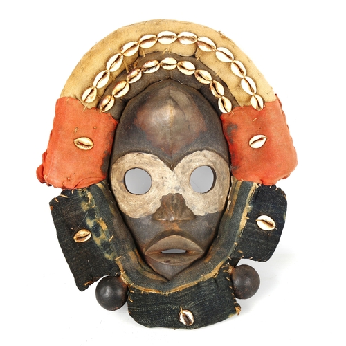 1357 - An African Dan carved and painted wood mask, with cowrie shell and textile surround, length 32cm