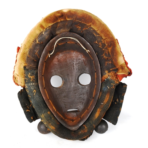 1357 - An African Dan carved and painted wood mask, with cowrie shell and textile surround, length 32cm