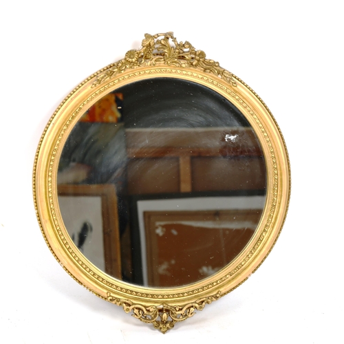 1380 - A circular Victorian gilt-gesso framed wall mirror, with floral pediment, height 54cm, width 46cm