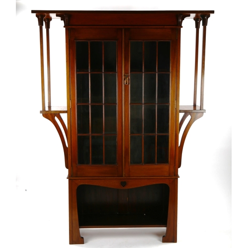 1400 - An Art Nouveau mahogany bookcase of stylised form with lattice-glazed doors, flanked by projecting s... 