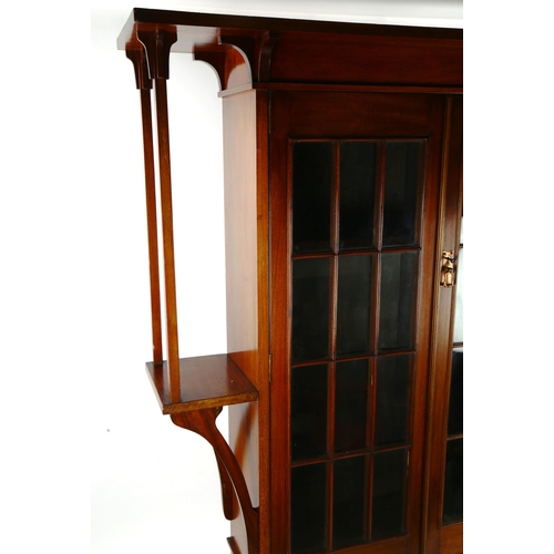 1400 - An Art Nouveau mahogany bookcase of stylised form with lattice-glazed doors, flanked by projecting s... 