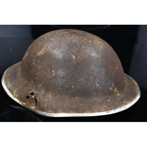 1223 - A military tin helmet with a sniper's bullet hole