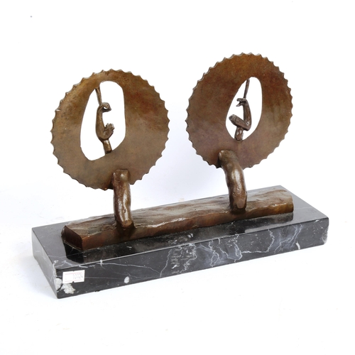 72 - A surrealist bronze sculpture, flexed arms within saw wheels, unsigned, on veined black marble base,... 