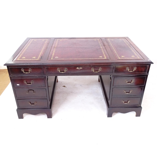 2029 - A reproduction mahogany veneered twin-pedestal writing desk, with a a 3-section red leather tooled t... 