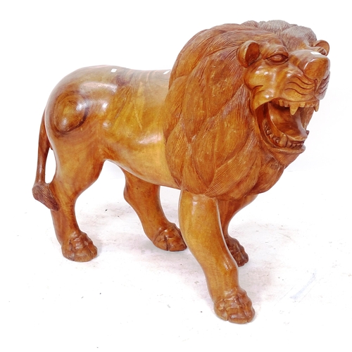 2050 - A carved hardwood study of a lion, length 90cm, H77cm