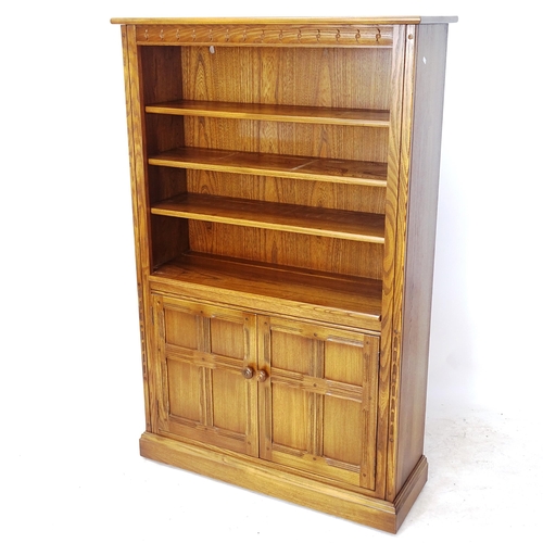 2066 - An Ercol Golden Dawn bookcase, with 2 adjustable open shelves, and a cupboard enclosed by 2 panelled... 