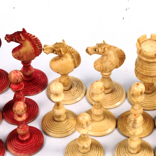 1021 - A 19th century red and white stained bone chess set, King height 8cm, in original poker-work decorat... 