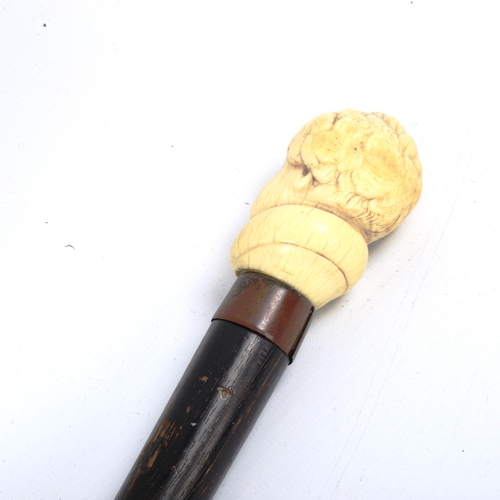 1069 - A carved ivory-handled walking cane, depicting the head of a man