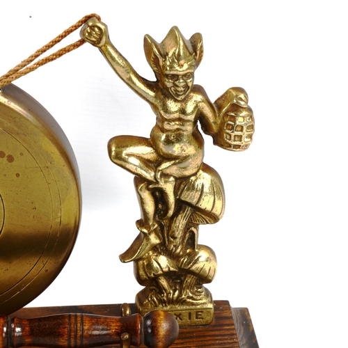 1118 - A brass gong supported by imp figures, on oak base, length 28cm