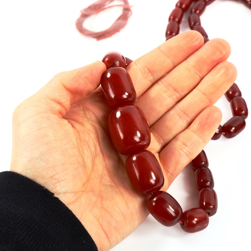 363 - A graduated single-strand cherry red amber barrel bead necklace, bead lengths 26.6mm to 15.2mm, neck... 