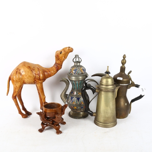 502 - Omani coffee pots, tallest 31cm, a brass hot water jug, a stand, and a leather camel