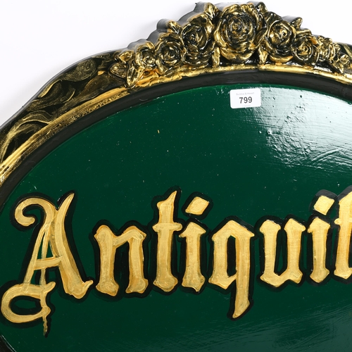 799 - An oval painted wood Antiquities sign, 67cm across