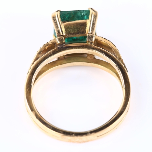 110 - A late 20th century solitaire emerald ring, unmarked gold settings with textured shoulders and squar... 