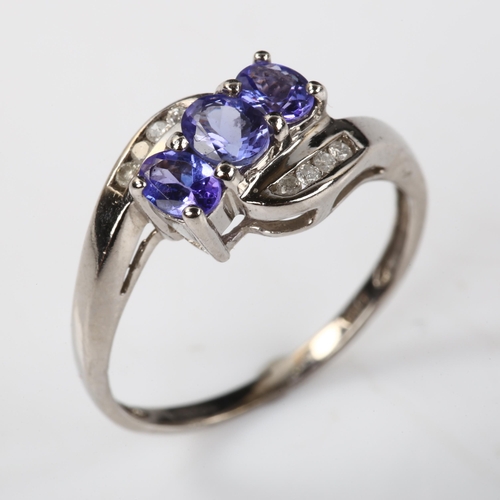 375 - A modern 9ct white gold tanzanite and diamond crossover ring, set with oval mixed-cut tanzanite and ... 