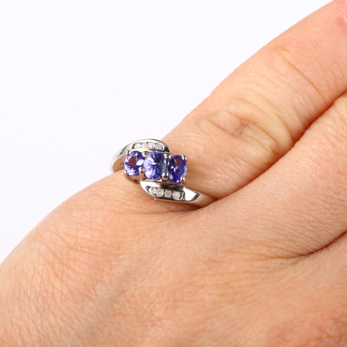 375 - A modern 9ct white gold tanzanite and diamond crossover ring, set with oval mixed-cut tanzanite and ... 