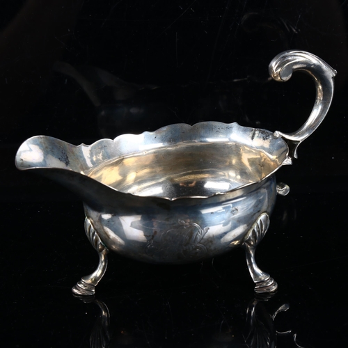 411 - A George II silver sauce boat, with a scalloped rim, scrolled acanthus leaf handle and hoof feet, by... 