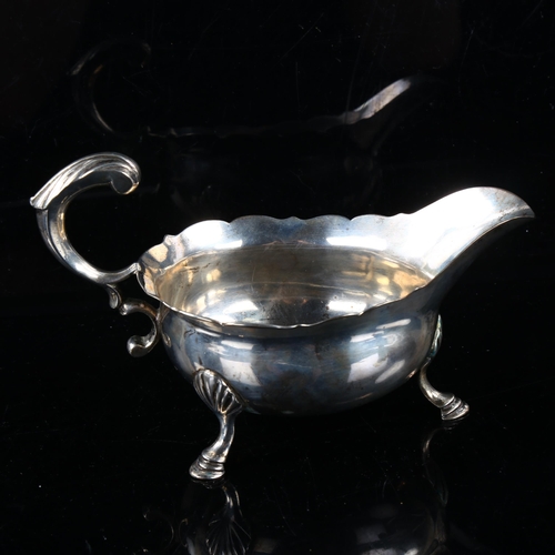 411 - A George II silver sauce boat, with a scalloped rim, scrolled acanthus leaf handle and hoof feet, by... 