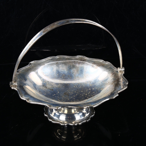 451 - MAPPIN & WEBB - a George V silver swing-handled fruit basket, reeded scalloped rim on pedestal base,... 