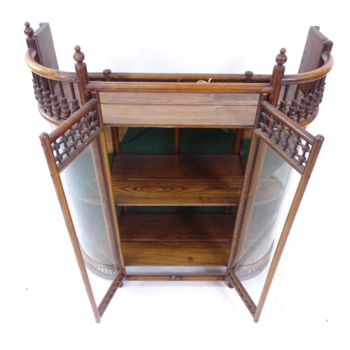 2101 - An oak Arts and Crafts style bow-end hanging display cabinet, with 2 glazed doors and 2 fixed shelve... 