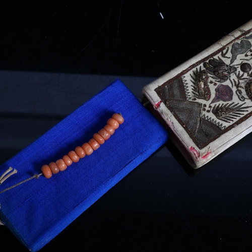 211 - A Chinese embroidered silk case, containing a blue silk covered notebook and a short string of coral... 